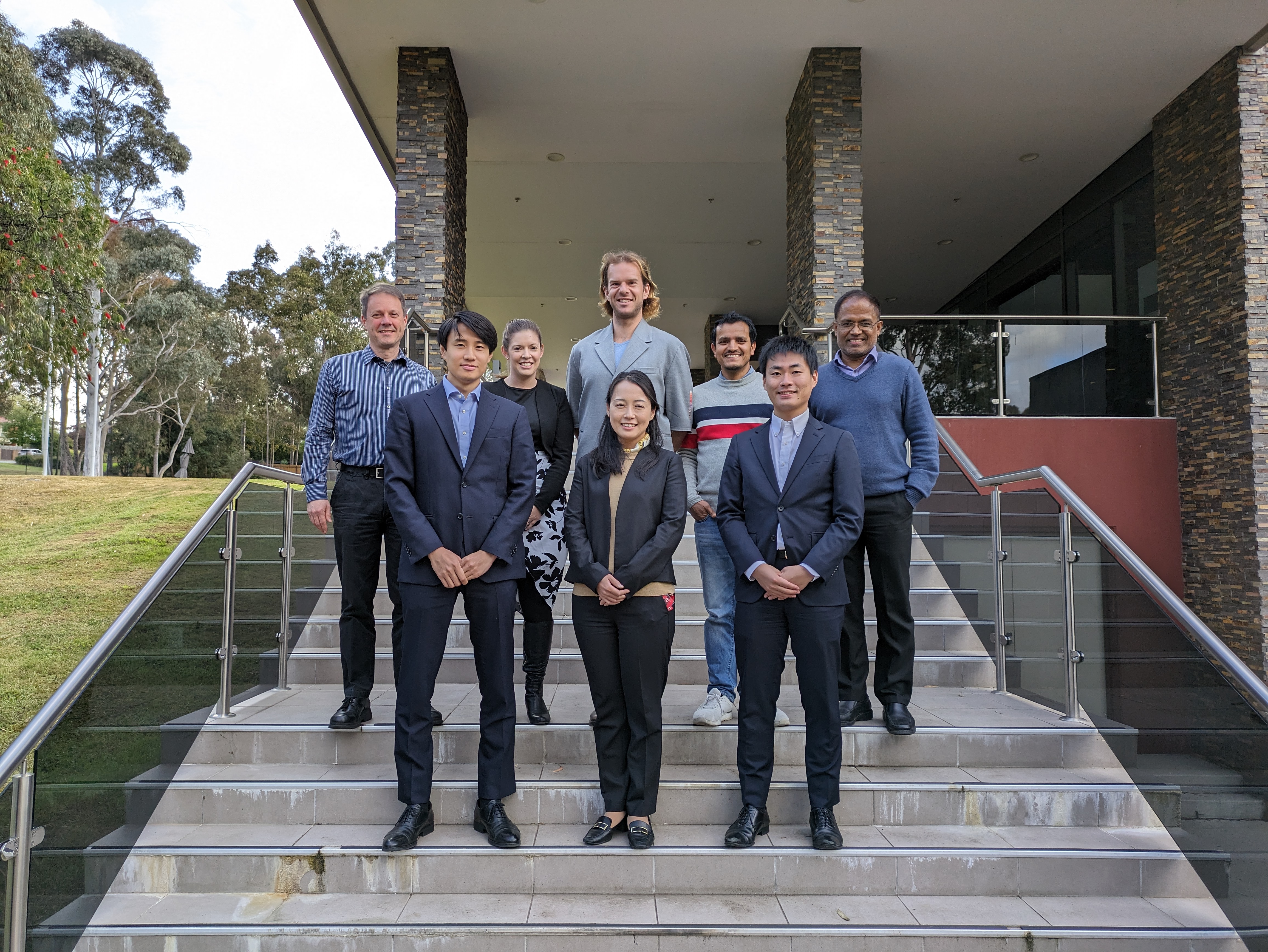 A group of people stand on stairs in a neat formation