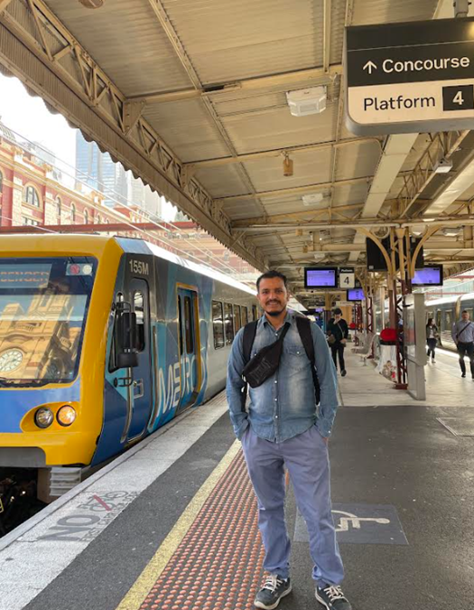 A man standing at Flinders St Station with a bumbag