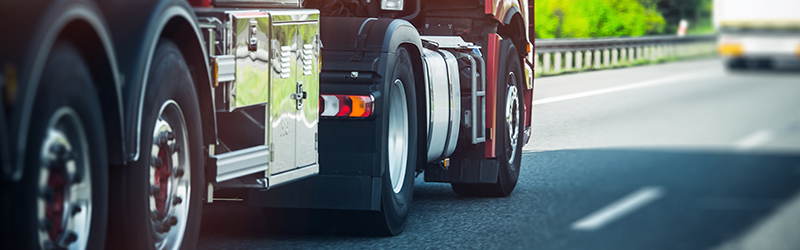 Close-up of bottom half of a large truck driving along a road